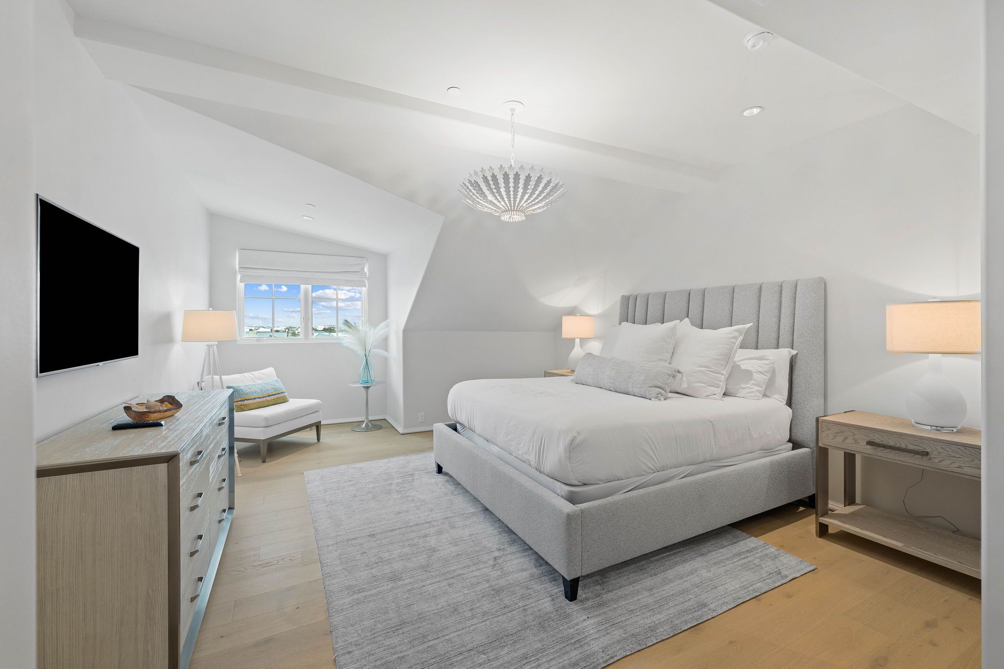 Un dormitorio moderno con una cama grande, un televisor de pantalla plana, un escritorio y una ventana con vistas.