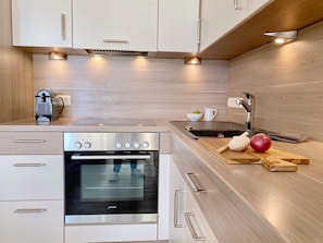 Une cuisine moderne dotée d’un four encastré, d’un évier et de plans de travail en bois.