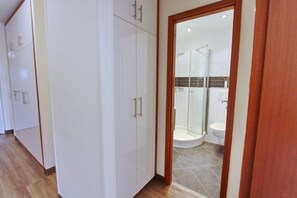 Une chambre d’hôtel avec un plancher en bois, des murs blancs et une cabine de douche en verre.