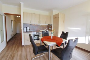 Une cuisine moderne avec des meubles en bois, une table à manger avec quatre chaises et une machine à café.