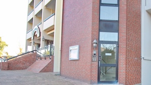 Un edificio con facciata in mattoni rossi, ingresso in vetro e una scalinata che conduce all'ingresso.