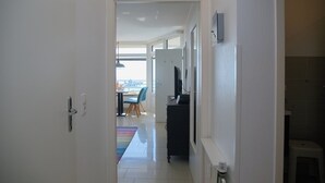 A hallway leading to a dining area with a table and chairs, a black cabinet, and a window. - Grömitz-center I App. 657 Inkl. Wlan (Grömitz)