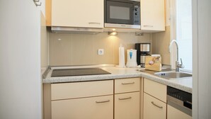 A compact kitchen with a microwave, coffee maker, and dishwasher. - Grömitz-center I App. 657 Inkl. Wlan (Grömitz)