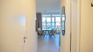 A hotel corridor leading to a dining area with a table and chairs, a large mirror, and a view of the outside. - Brookgang 47d Doppelhaushälfte Inkl. Wlan (Grömitz)