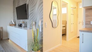 A modern kitchen with white cabinetry, a built-in oven, and a countertop with a coffee maker and decorative items. - Brookgang 47d Doppelhaushälfte Inkl. Wlan (Grömitz)