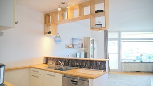 Eine moderne Küche mit Holzböden, einem Geschirrspüler und einem großen Fenster.