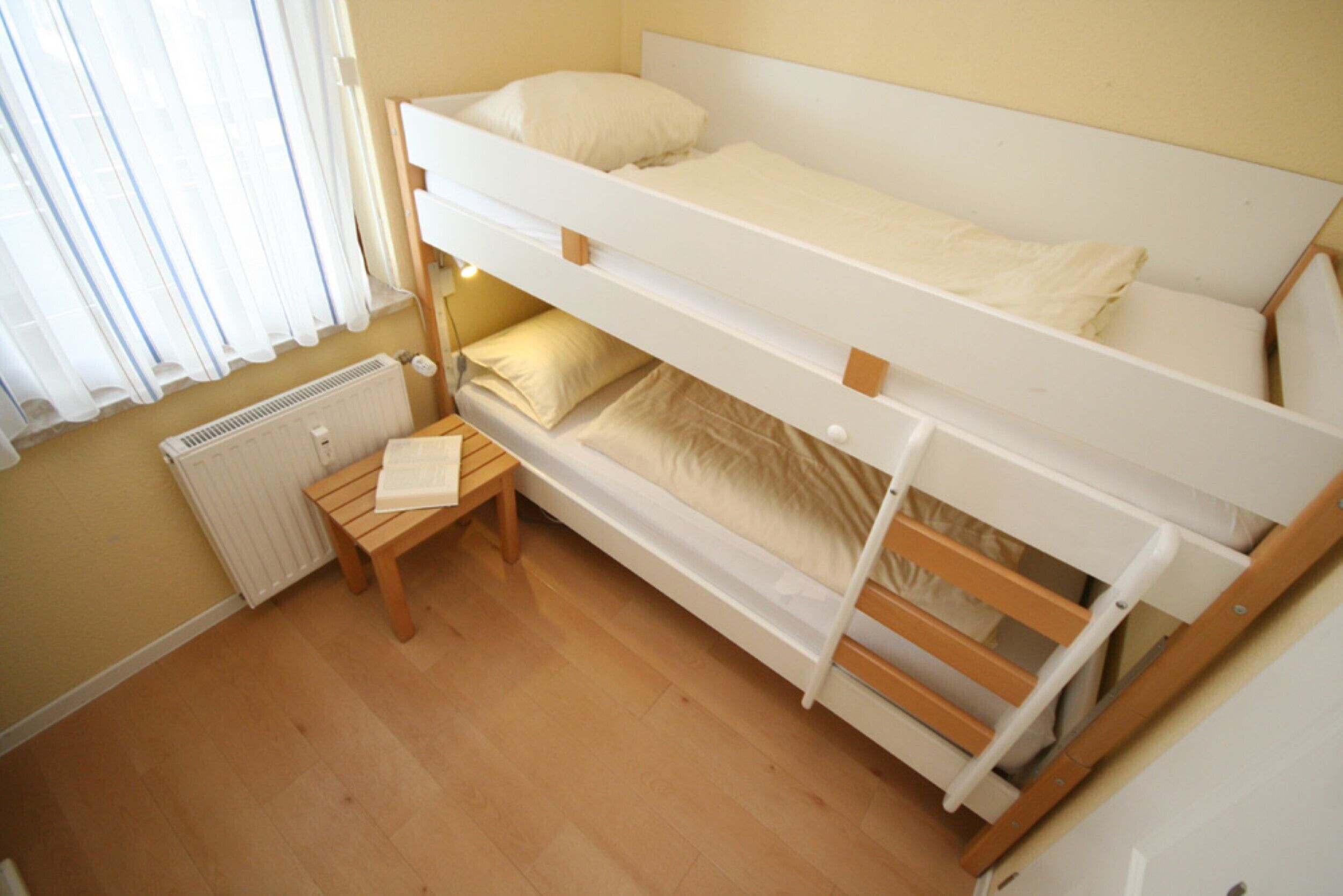 Ein Schlafraum mit Etagenbetten, einem Holztisch und einer Heizung.