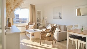 Un salon moderne avec un canapé, des fauteuils, une table à manger et une vue sur la ville.