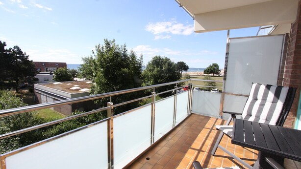 Un balcon avec vue sur la mer, un tableau blanc et du mobilier d’extérieur.