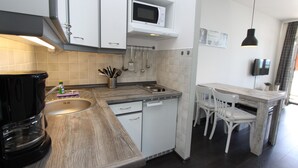Une cuisine moderne avec des meubles blancs, un four à micro-ondes, une machine à café et un coin repas comprenant une table et des chaises.