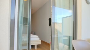 A hotel room with a bed, a chair, and a TV mounted on the wall.