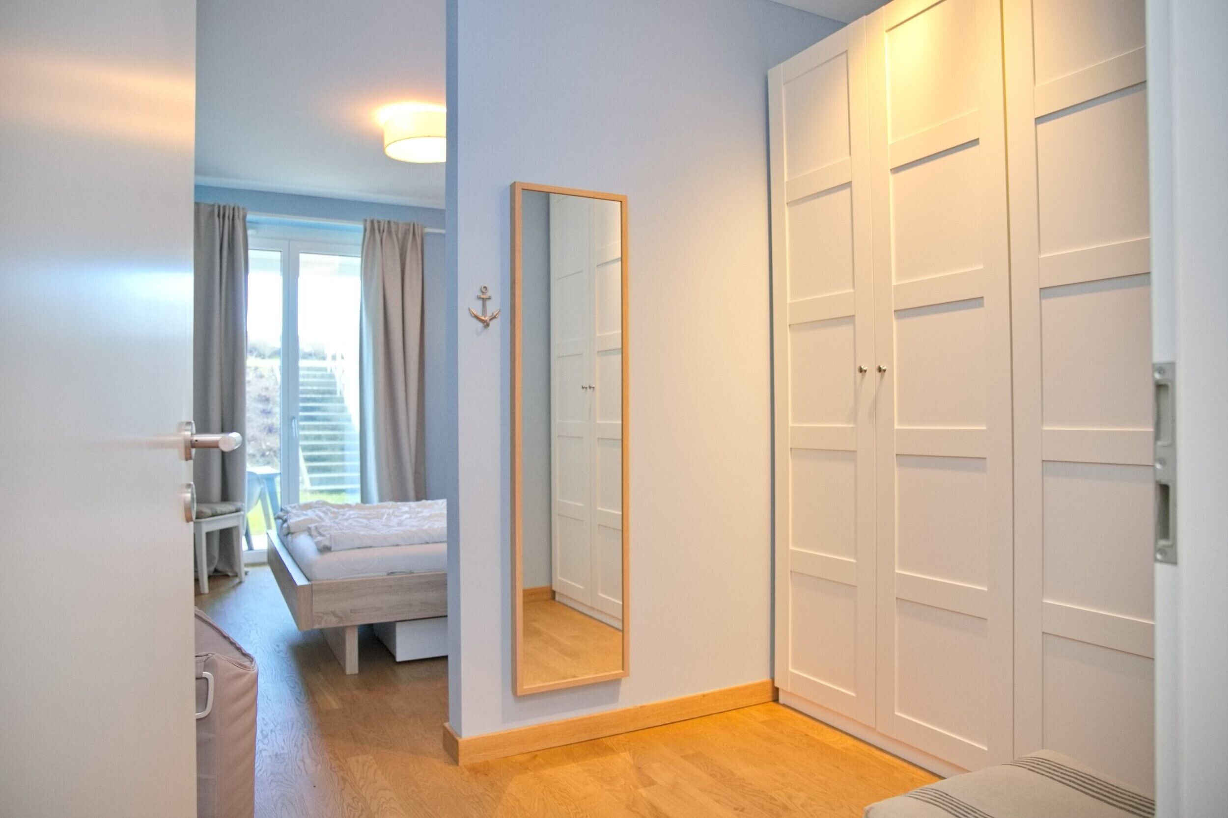 A bedroom with a bed, a large mirror, and a wardrobe.