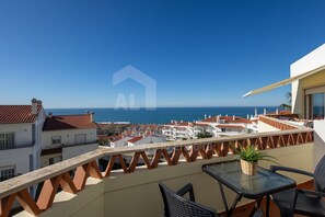 A balcony with a view of the sea, a table with a plant, and a chair. - Bela Vista Apartment by Acasadascasas (Mafra)