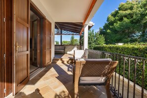 Un espacio al aire libre cubierto con una silla de mimbre, una mesa y vistas al jardín.