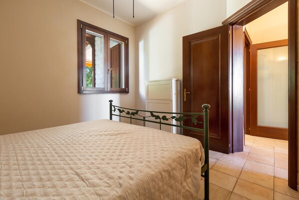 Un dormitorio con cama, ventana, puerta y radiador.