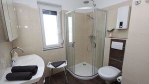 Une salle de bain moderne avec une douche à parois de verre, un lavabo blanc et des toilettes.