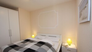 Une chambre à coucher comprenant un lit, deux tables de chevet, une commode et une armoire.