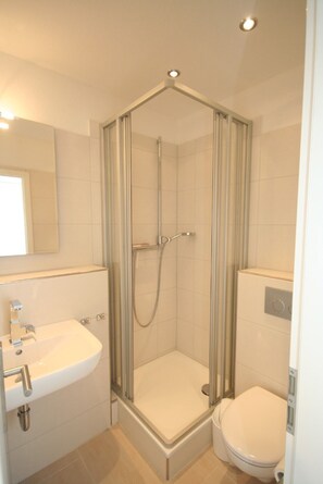 A modern bathroom with a glass-enclosed shower, a sink, and a toilet. - Am Brandungsbad App. 3.5 Inkl. Wlan (Grömitz)