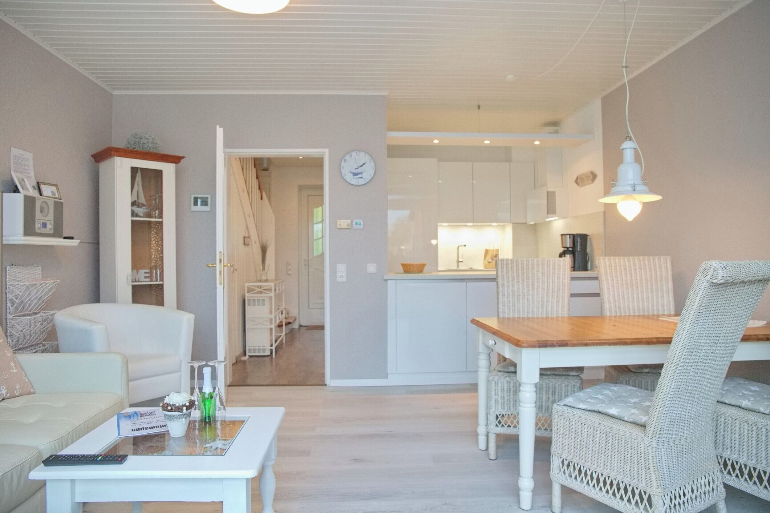 Una sala de estar moderna con comedor, una cocina al fondo y un reloj en la pared.