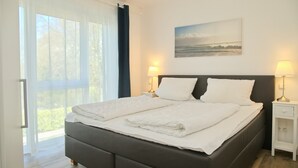 A neatly made double bed with white linens, a dark headboard, and two bedside tables with lamps. - Christian-westphal-str. 35, App. Mermaid Inkl. Wlan und Sauna (Grömitz)