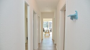 A hallway with white walls and wooden flooring leading to a dining area with a table and chairs. - Christian-westphal-str. 35, App. Mermaid Inkl. Wlan und Sauna (Grömitz)