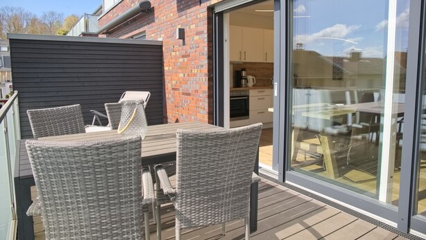 A patio with wicker furniture, a brick wall, and a sliding glass door leading to a kitchen. - Christian-westphal-str. 35, App. Mermaid Inkl. Wlan und Sauna (Grömitz)