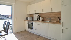 A modern kitchen with white cabinets, a wooden countertop, a built-in oven, a microwave, and a coffee maker. - Christian-westphal-str. 35, App. Mermaid Inkl. Wlan und Sauna (Grömitz)