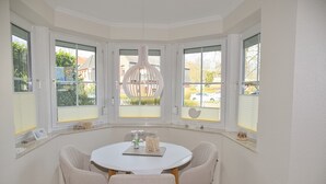 En spiseplads med et rundt bord, fire stole og en hængende lampe.