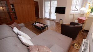 Ein Wohnzimmer mit einer Couch, einem Couchtisch, einem Fernseher und einer Lampe.