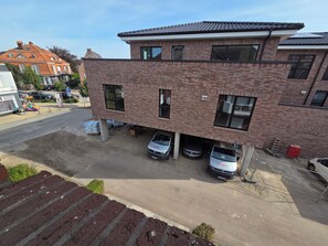 A multi-story building with a brick facade, multiple windows, and a parking area with several cars. - Holiday am Deich App. 42 Inkl. Wlan und Strandkorb (Grömitz)
