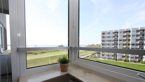 A window with a view of a building and a grassy field. - Hanseat II App. 149 Inkl. Wlan (Grömitz)