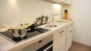 Eine moderne Küche mit eingebautem Herd, einem Topf voller ungekochter Pasta und einem Spülbecken.