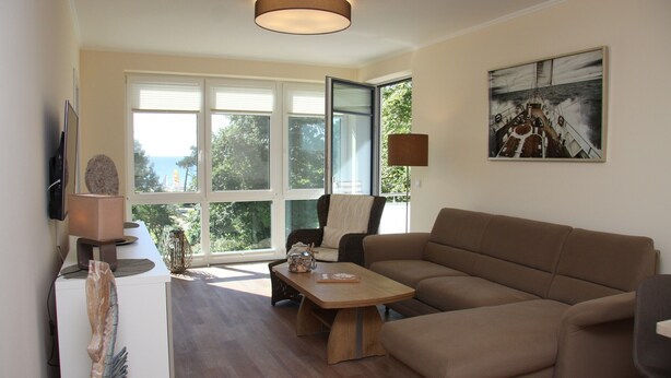 Ein modernes Wohnzimmer mit großem Fenster, einer Couch, einem Couchtisch und einem Gemälde an der Wand.