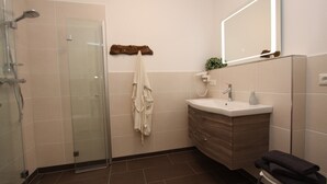 Ein modernes Badezimmer mit Duschkabine aus Glas, Waschtisch mit Spiegel und Handtuchhalter.