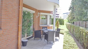 Eine Terrasse mit Tisch, Stühlen, einem Topfpflanzen und einer Ziegelwand.