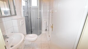 A bathroom with a shower, sink, toilet, and a mirror. - Dornröschen Wohnung 3 (Grömitz)