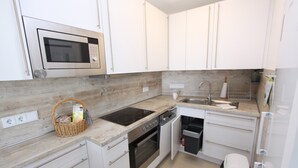 Une cuisine moderne avec des armoires blanches, un four à micro-ondes, une cuisinière et un évier.
