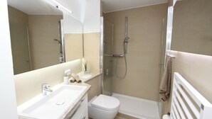 Une salle de bain moderne avec un lavabo blanc, des toilettes et une douche à l’italienne.