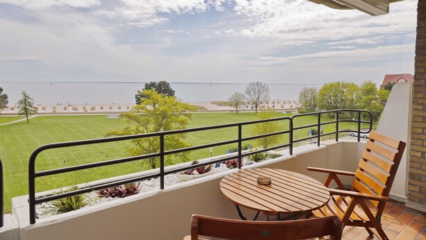 Un balcone con vista su un campo verde e un edificio in lontananza.