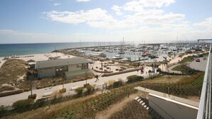 Un puerto deportivo con barcos amarrados, una zona de playa y un edificio con techo inclinado.