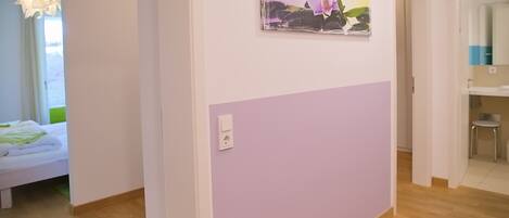 Una habitación con una cama, un cuadro de una orquídea colgado en la pared y suelo de madera.
