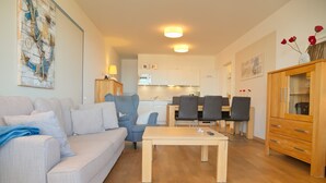 Una sala de estar con sofá, mesa de centro y comedor con sillas y aparador.