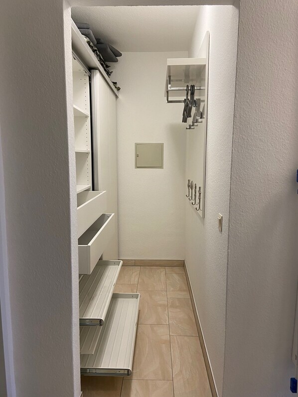 A narrow hallway with a white wall, a small shelf unit, and a radiator.