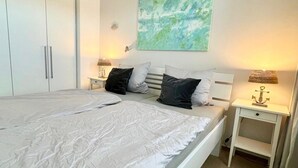 Makuuhuoneessa on suuri sänky, kaksi yöpöytää, vaatekaappi ja seinälle ripustettu taideteos.