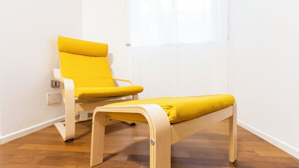 Una silla y un banco amarillos en una habitación con suelo de madera y paredes blancas.