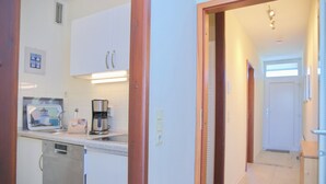 A kitchen with white cabinets, a dishwasher, and a coffee maker. - Seeschlößchen App. 113 Inkl. Wlan (Grömitz)