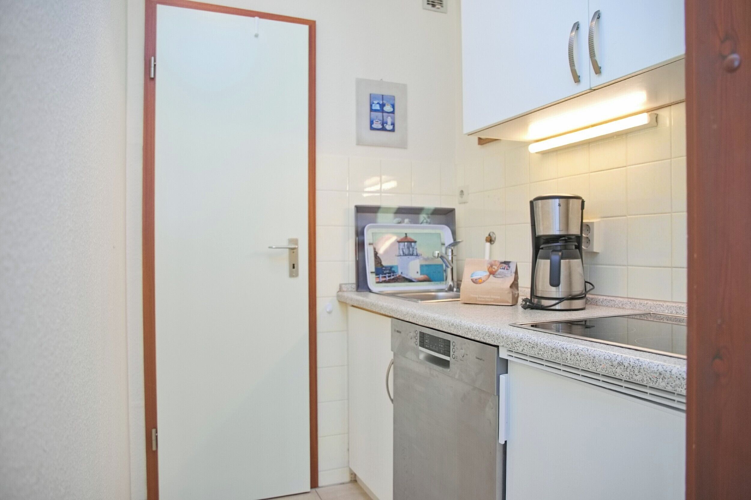 A compact kitchen with a dishwasher, a coffee maker, and a microwave on the countertop.