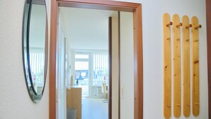 A hallway with a wooden bench, a mirror, and wooden pegs on the wall. - Seeschlößchen App. 113 Inkl. Wlan (Grömitz)