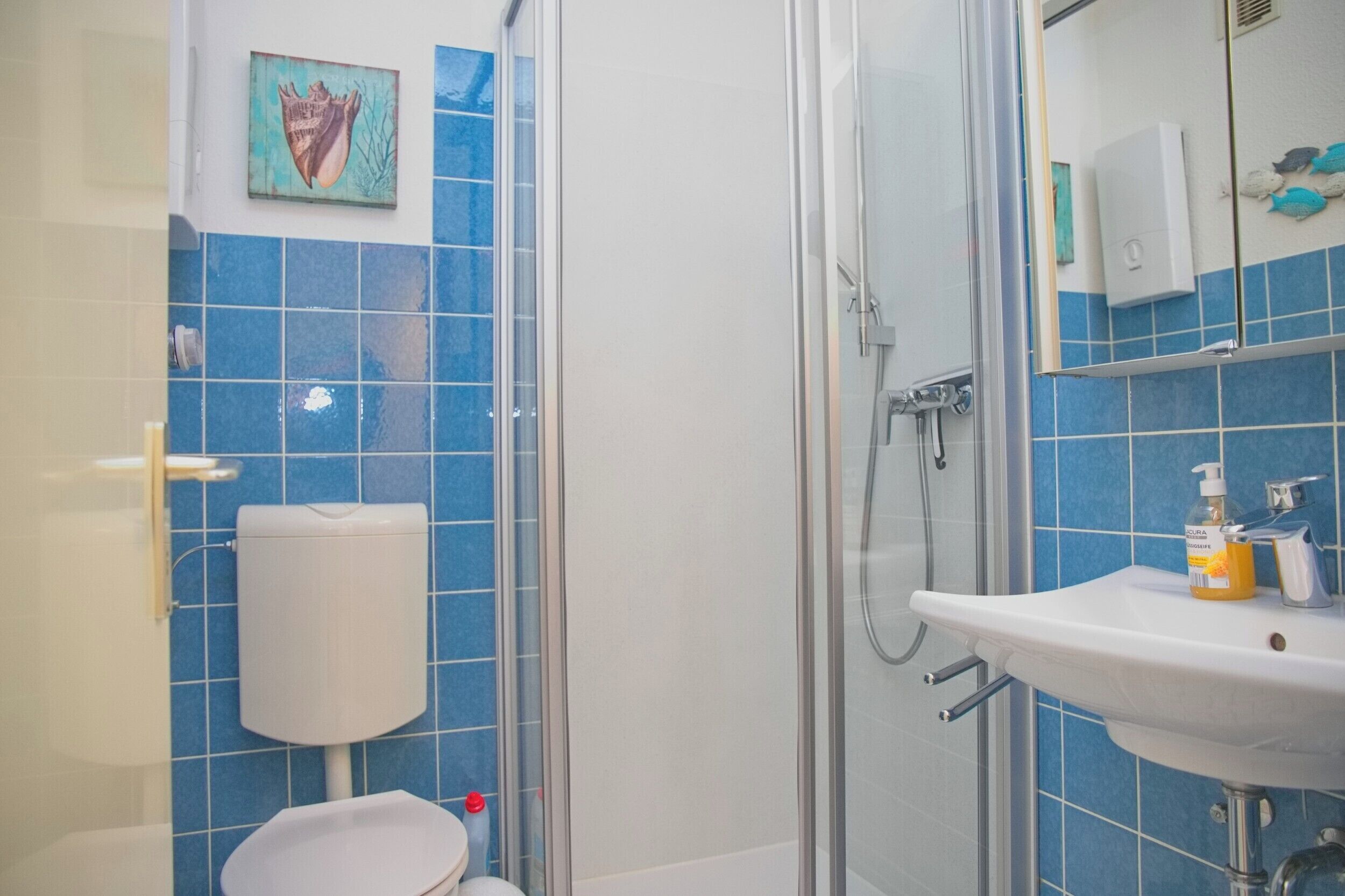 Een badkamer met toilet, douchecabine, wastafel en een handdesinfecterend middel.