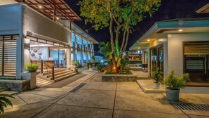A modern hotel with a spacious courtyard, a central tree, and a well-lit entrance. - Ora Beach Resort (El Nido)
